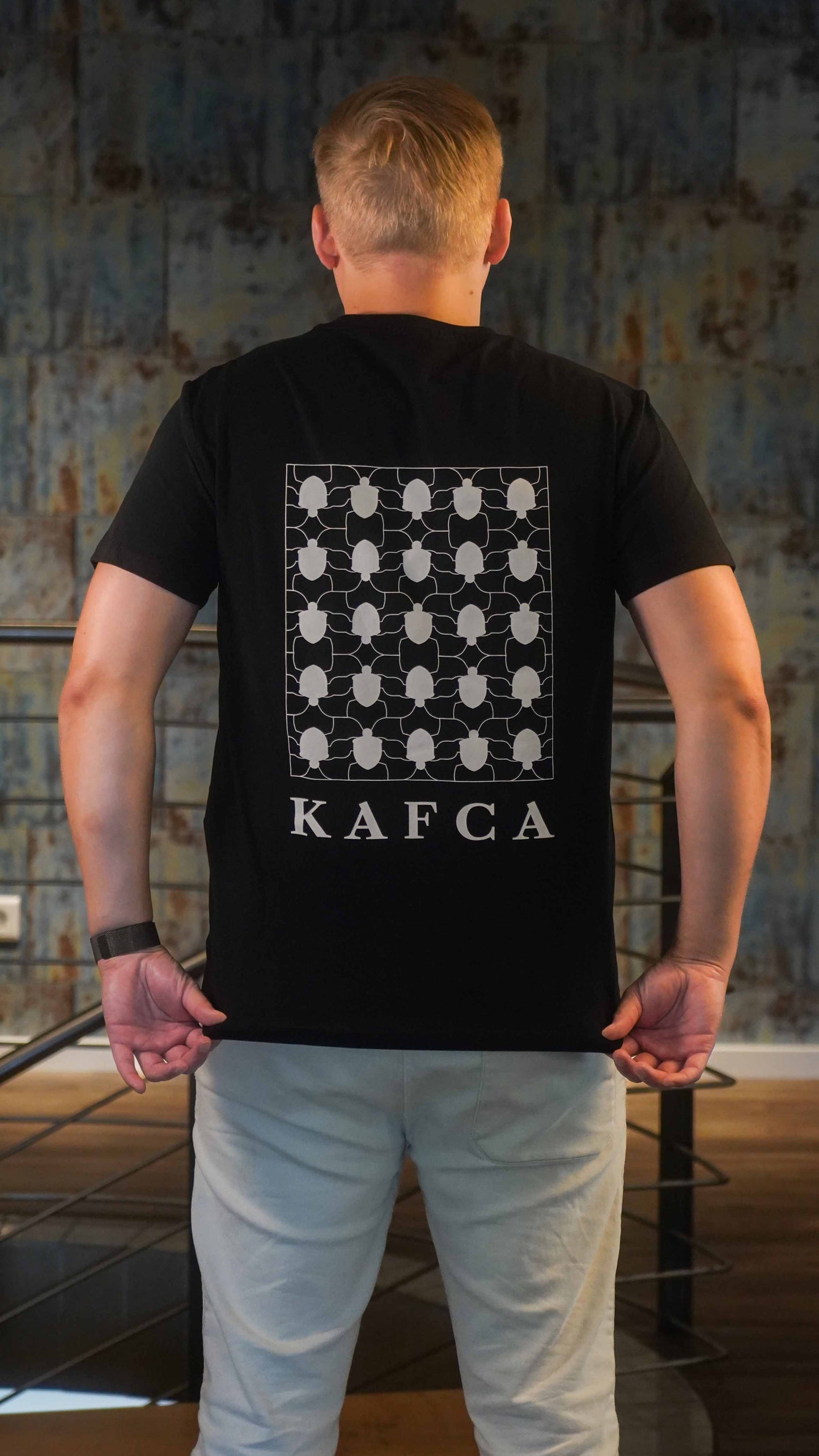 KAFCA-Couture T-Shirt in schwarz von hinten mit Käfer-Pattern in beige als Vollbild