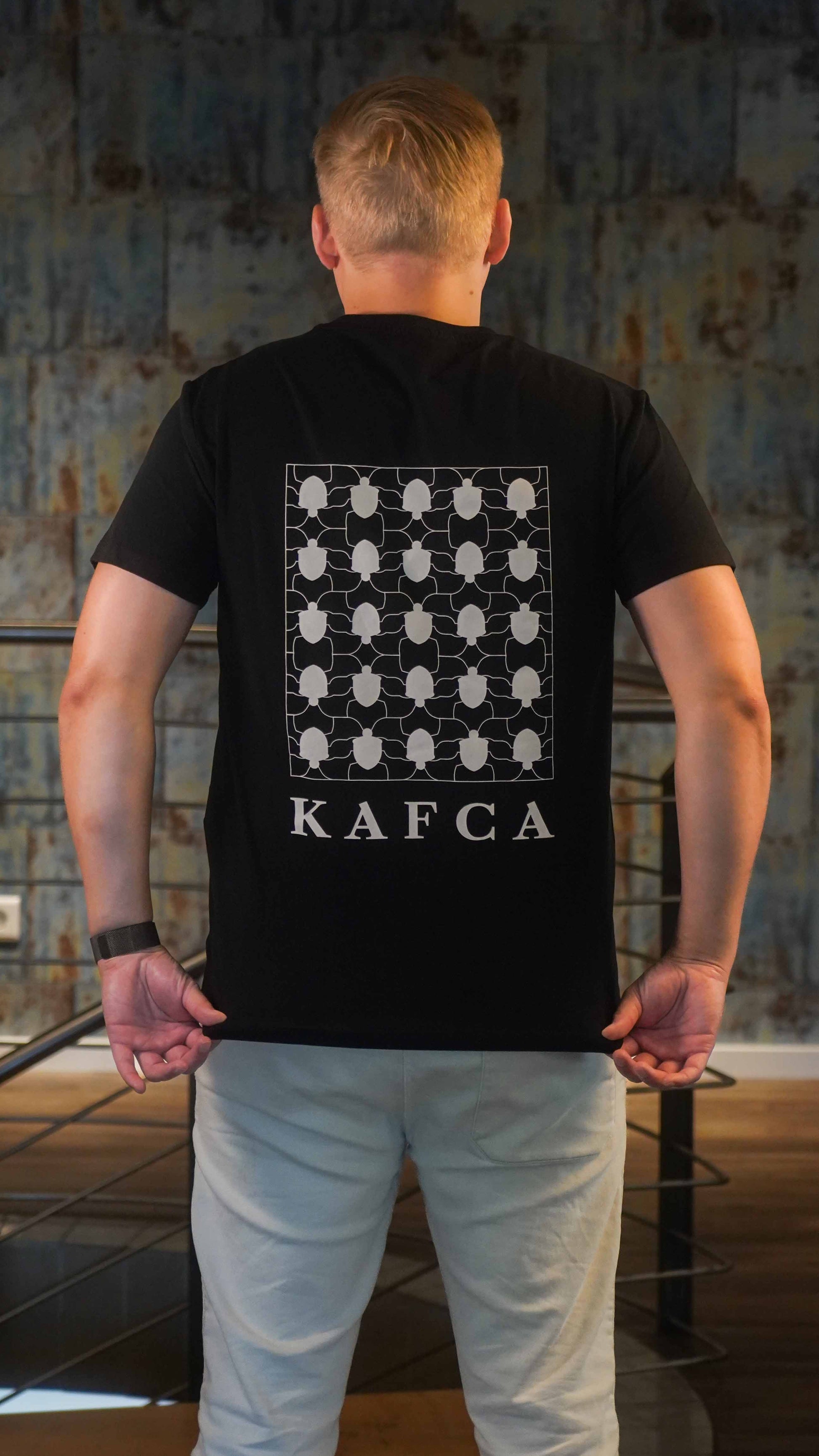 KAFCA-Couture T-Shirt in schwarz von hinten mit Käfer-Pattern in beige als Vollbild